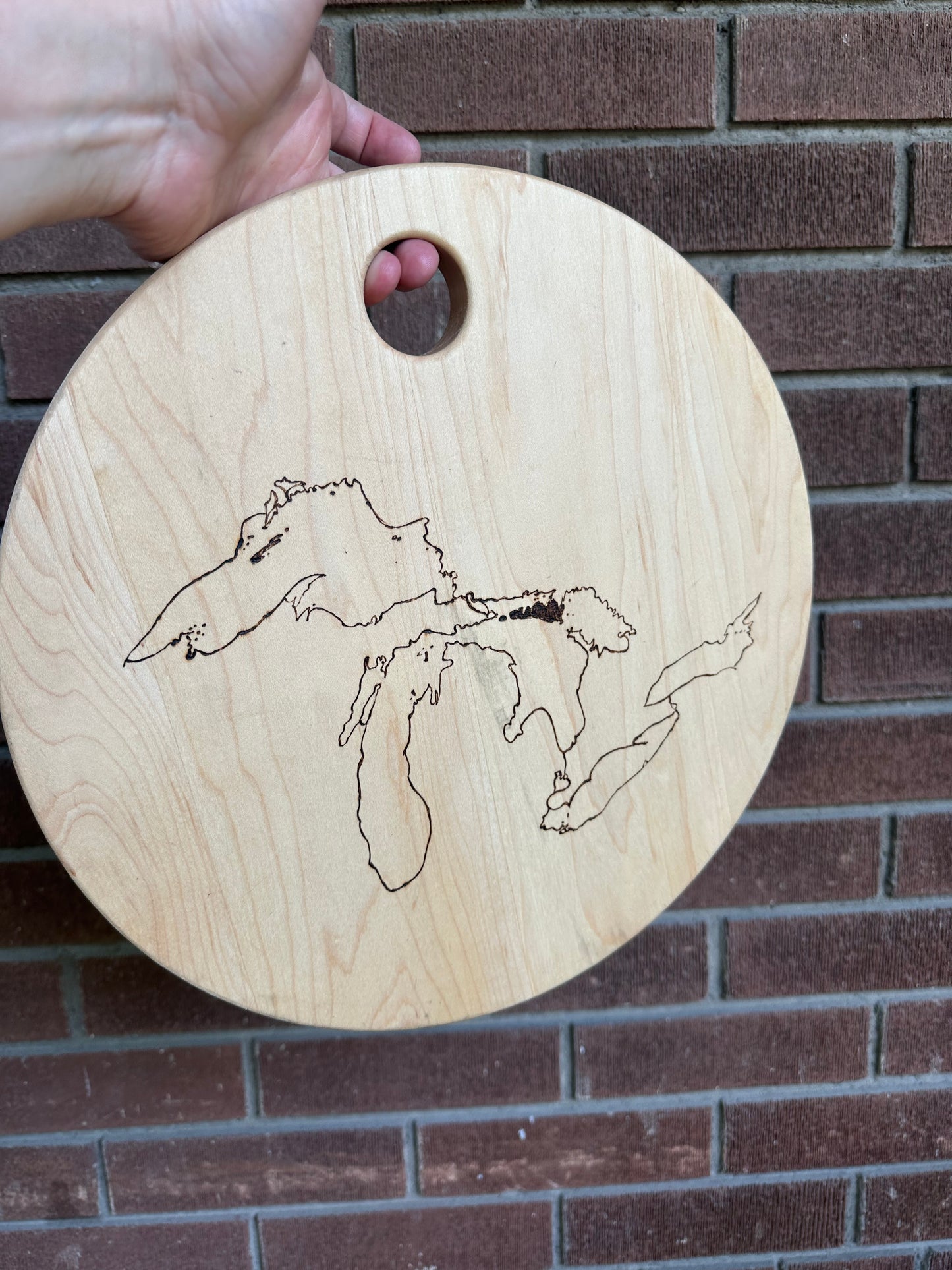 Image displays a brick wall in the background with a 13" round serving dish in front. Wood dish has The Great Lakes burned into it using a pyrography machine.