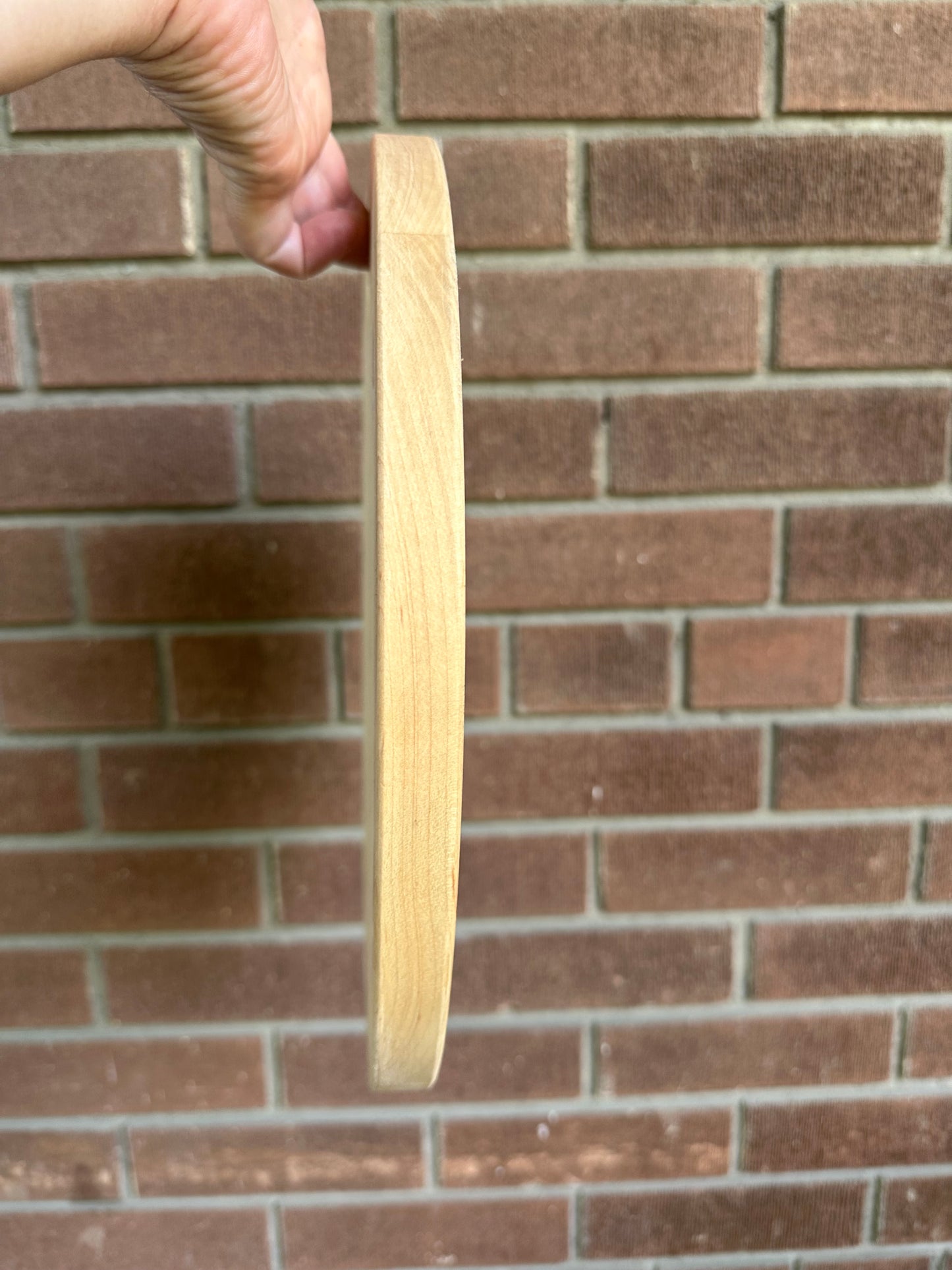Side profile of Great Lakes Serving Dish with brick in the background and a hand holding the dish up.