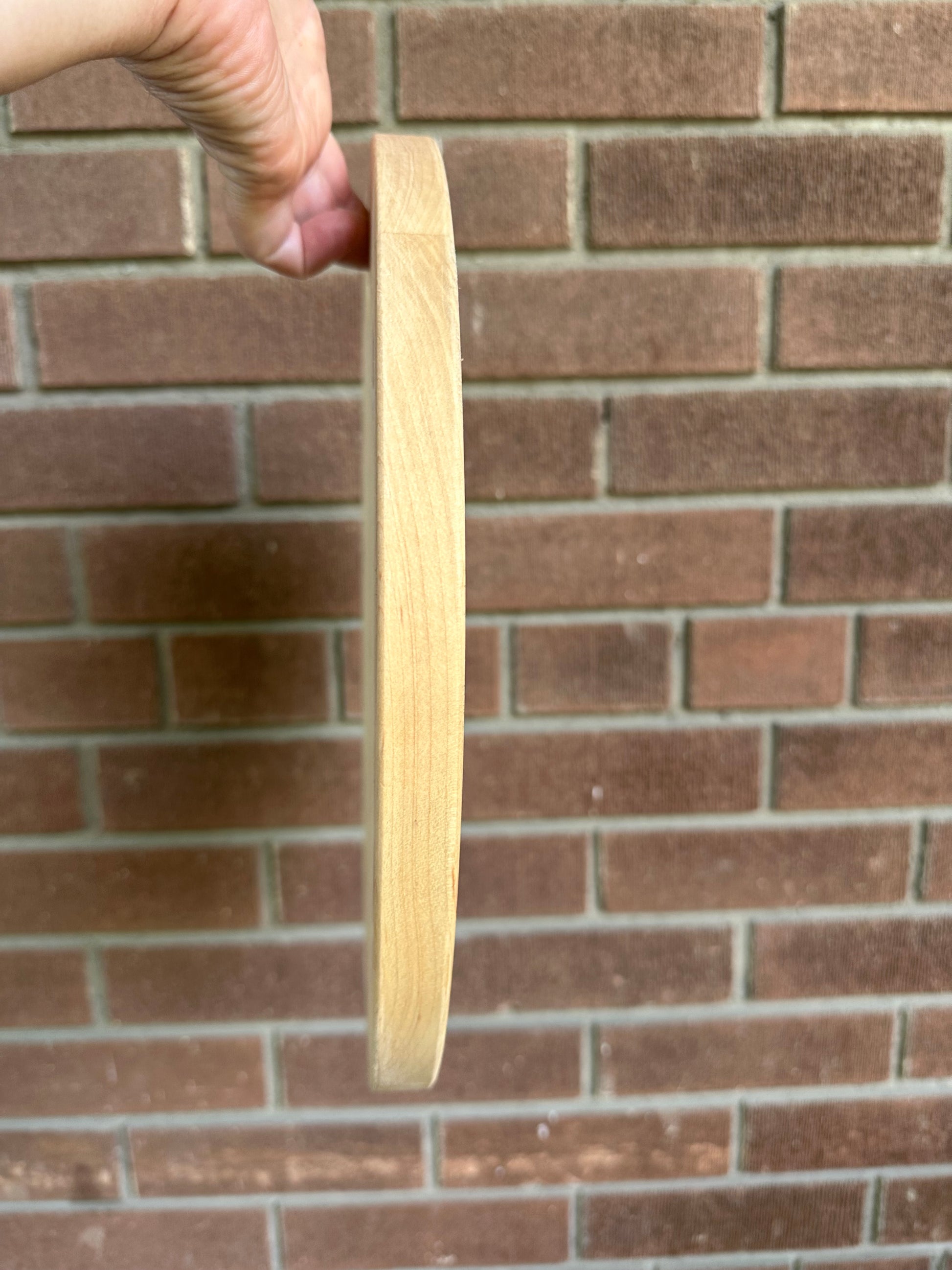 Side profile of Great Lakes Serving Dish with brick in the background and a hand holding the dish up.