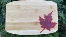 Load image into Gallery viewer, Pre-treated bamboo mini serving tray is small enough for two kids hands or one adult hand for coffee! The Canadian maple leaf has been hand carved and filled with red epoxy. Each pieces is treated with Walrus Oil Food-safe Cutting board oil. 
